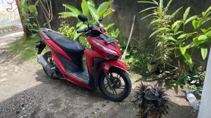 een rode scooter geparkeerd langs de kant van de weg bij Lanina homestay in Ipi