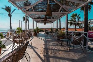 a patio with chairs and tables and palm trees at Hostal Playa Pitaya in Torre del Mar