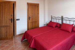 a red bed with red pillows in a bedroom at Casa rural BUSEO in Chera