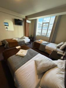 een hotelkamer met 3 bedden en een raam bij Hotel Camino Real Puno in Puno