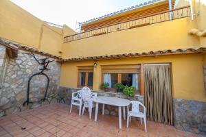 a patio with white chairs and a table and a building at Casa rural BUSEO in Chera
