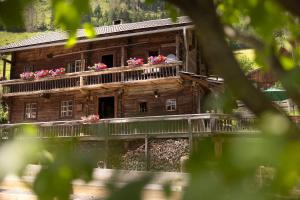 an old wooden house with flowers on the balcony at Chalet Mühlburger in Gruben