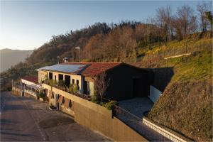 a house on the side of a hill next to a road at El Cielo - Rooms with Panoramic View & El Carnicero Restaurant in Cornedo Vicentino