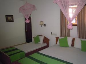 2 Betten in einem Zimmer mit Grün und Weiß in der Unterkunft Devi Tourist Home in Polonnaruwa