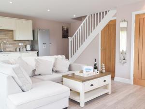 a living room with a white couch and a table at Brook View Cottage in Pembrokeshire