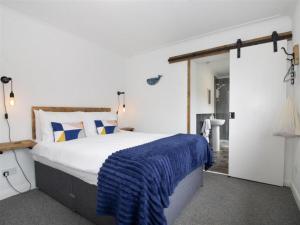 a bedroom with a large bed with a blue blanket on it at Ocean View Bar & Rooms in Laide