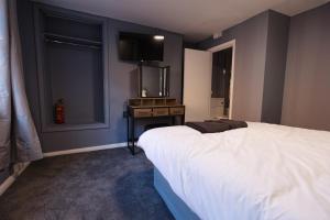 a bedroom with a bed and a desk and a television at Monk and Tipster in Towcester