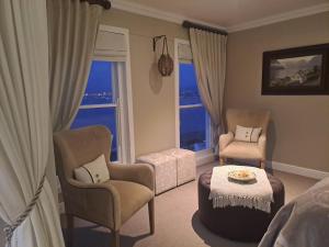 a room with two chairs and a table and a bed at Boutique Inn - Serenity in Gordonʼs Bay