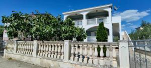 a white fence in front of a house at Apartments Villa Granda Tolic in Biograd na Moru