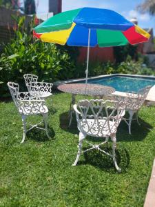 a table and chairs with a colorful umbrella next to a pool at Wisla Rellowed in Manuel B. Gonnet