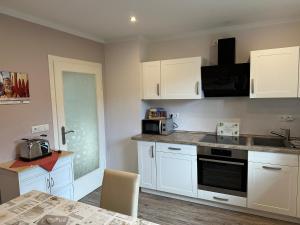 a kitchen with white cabinets and a counter top at FeWo Am Reinhardsberg in Friedrichroda +10 photos