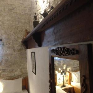 1 dormitorio con cama de madera y espejo en Konaku Guest house, en Gjirokastra
