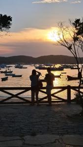 Twee mensen staan op een bankje en kijken naar het water. bij L&S casa da lagoa in Búzios