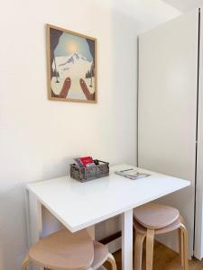a white table with two stools and a picture on the wall at Bellavista Morgins in Troistorrents