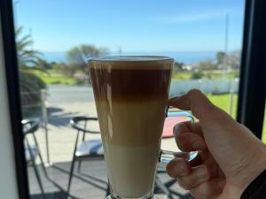 Iemand houdt een glas koffie omhoog. bij St Helena Bay Hotel in St Helena Bay