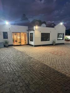 a white house with a brick driveway in front of it at Petron home in Kempton Park