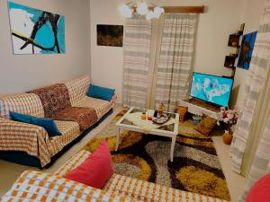 a living room with two couches and a tv at xanthi's sea front villas in Flámbouras