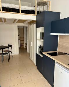 a kitchen with blue cabinets and a dining room with a table at Hotel Le Petit Baigneur Palavas Plage in Palavas-les-Flots