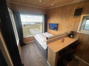 a small room with a bed and a large window at Unik og moderne microhytte med utsikt mot havet 40 A Otterlei Resort in Longva