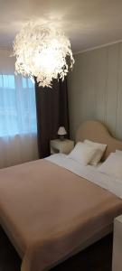 een slaapkamer met een groot wit bed met een kroonluchter bij Purjemaja in Otepää