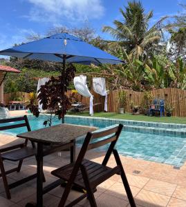 een tafel en stoelen met een parasol naast een zwembad bij Pousada Praia do Amor Pipa in Pipa
