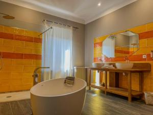 a bathroom with a tub and a sink and a mirror at Hôtel d'Alibert in Caunes-Minervois
