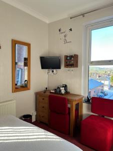 a bedroom with a bed and a desk and a television at Greylands Guest House in Llandrindod Wells