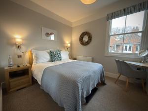 a bedroom with a bed and a desk and a window at The Ship Inn in Weybourne