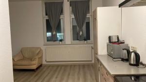 een keuken met een stoel, een magnetron en ramen bij Wohnung am Bahnhof in Schmalkalden