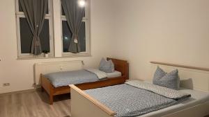 twee bedden in een kamer met twee ramen bij Wohnung am Bahnhof in Schmalkalden