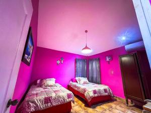 two beds in a room with pink walls at Rancho Colibrí in Acajutla +47 photos