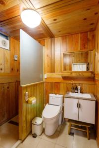 ein Bad mit einem WC, einem Waschbecken und Holzwänden in der Unterkunft 隱山居 海景包棟2-10人 in Jiufen