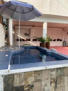 a swimming pool with an umbrella next to a house at Casa El nido de las flores in Oaxtepec