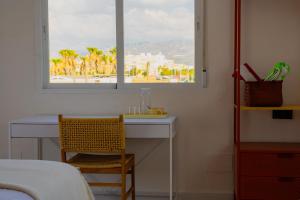 a bedroom with a desk and a window and a bed at Hostal Playa Pitaya in Torre del Mar
