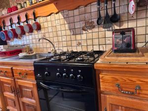 a kitchen with a black stove and a sink at Gîte Roc Suzadou in Ferrals-les-Montagnes