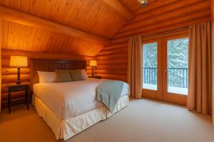 een slaapkamer met een bed en een groot raam bij Private A-Frame Log Cabin near Tremblant With Hot tub Game Room in Labelle
