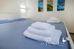 twee stapels handdoeken zittend op een bed bij Case Vacanze La Pavoncella in Teulada