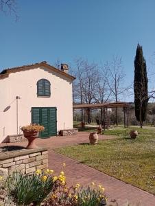 a white building with a green door in a yard at Podere la Campagnola in San Gimignano
