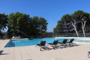 a row of lounge chairs next to a swimming pool at Golf apartment in Saumane-de-Vaucluse