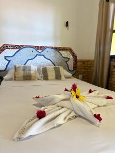 een bed met witte handdoeken en bloemen erop bij Pousada Praia do Amor Pipa in Pipa
