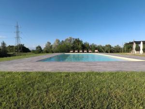 San GervasioGlamping Podere Poggiagrilli的田野中央的游泳池里摆放着椅子。