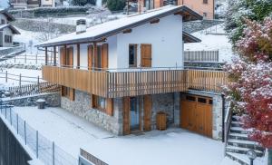 ein Haus im Schnee mit Balkon in der Unterkunft Baitèl de Sòt e Sura - Appartamenti in Gromo