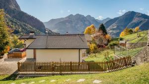 ein Haus mit einem Zaun und Bergen im Hintergrund in der Unterkunft Baitèl de Sòt e Sura - Appartamenti in Gromo + 71 Fotos