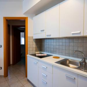 a kitchen with white cabinets and a sink at Tropicana Residence in Lido degli Estensi