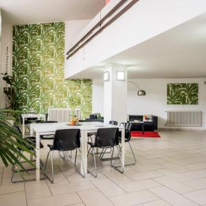 a dining room with a white table and black chairs at Tropicana Residence in Lido degli Estensi
