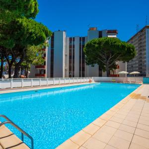 a large blue swimming pool with trees and buildings at Tropicana Residence in Lido degli Estensi