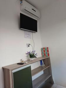 una televisione appesa a un muro con una scrivania di Studio Com Ar Condicionado na Manoel Novais a Serrinha