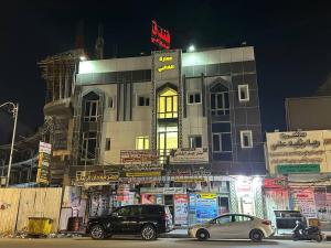 two cars parked in front of a building at night at فندق حمورابي Hammurabi Hotel in An Nāşirīyah