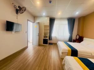 a hotel room with two beds and a flat screen tv at Ruby Hotel in Nhơn Trạch