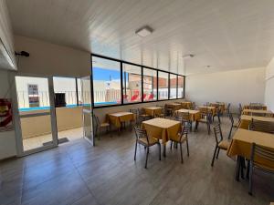 een eetkamer met tafels en stoelen en ramen bij Complejo Brisas Místicas in Las Grutas